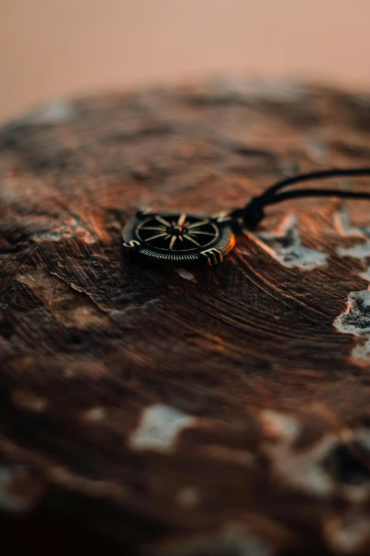 an antique pendant sitting on top of a piece of wood