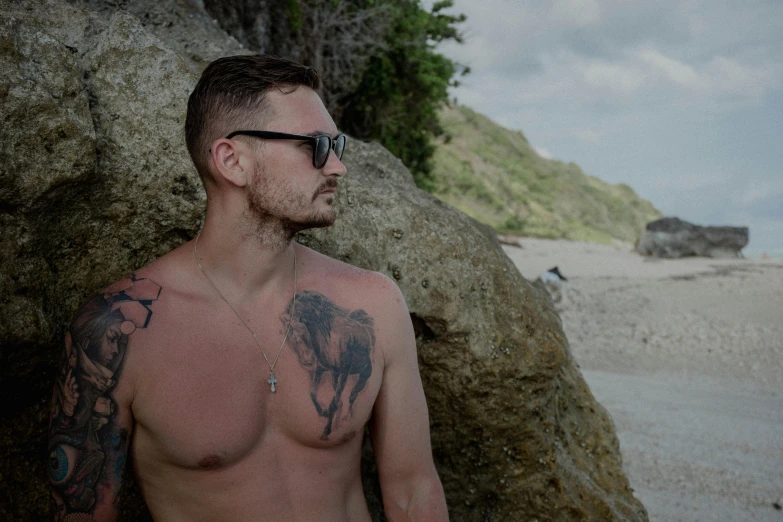 a man on the beach with rocks and some trees