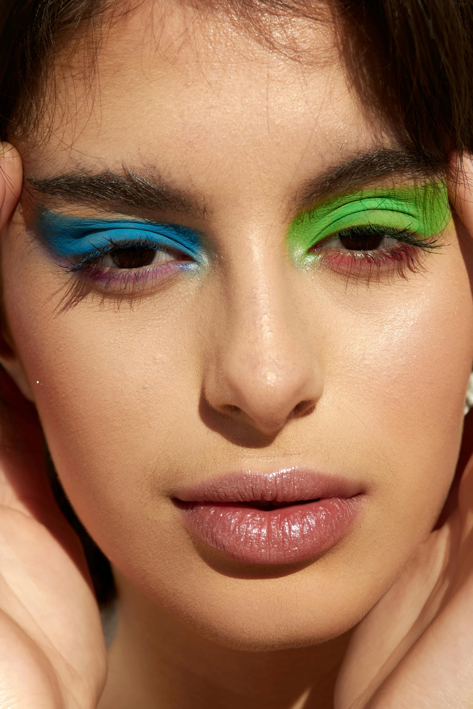 a woman is wearing green, blue and purple eye shadows