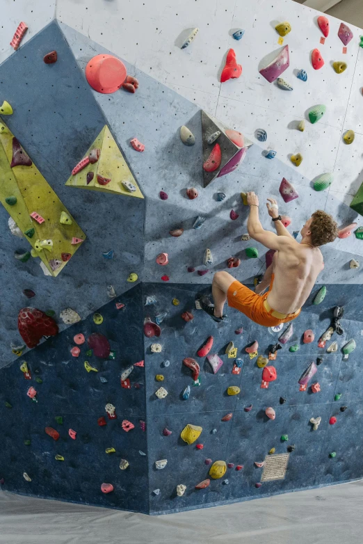 a man is climbing up the side of a climbing wall