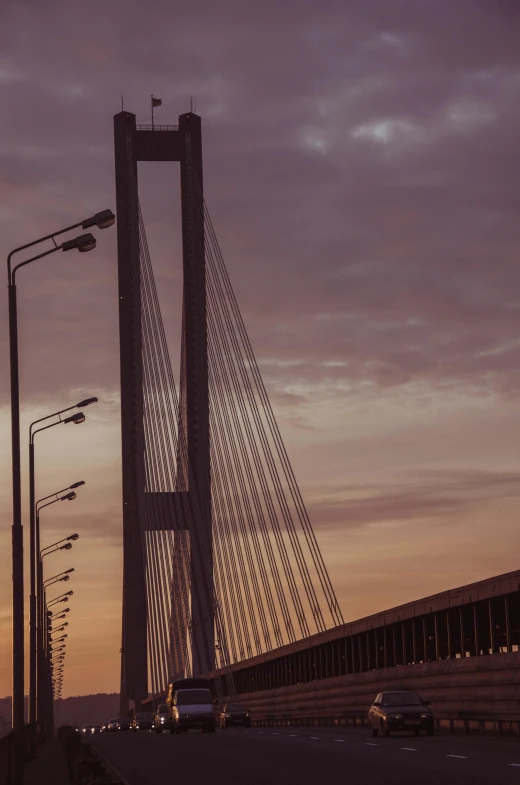 an suv driving on the road with a large suspension bridge in the background