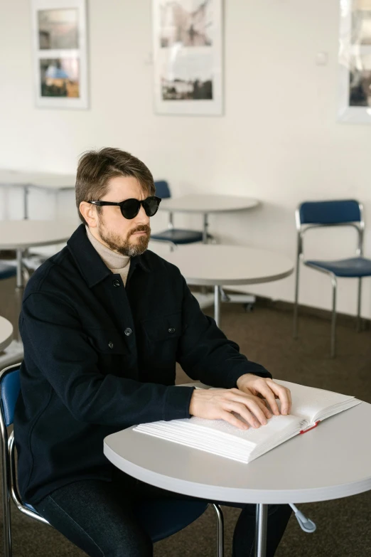 a man sitting at a white table using a laptop computer