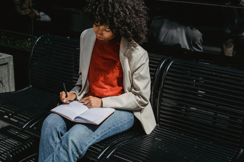 a woman sits on a park bench while writing