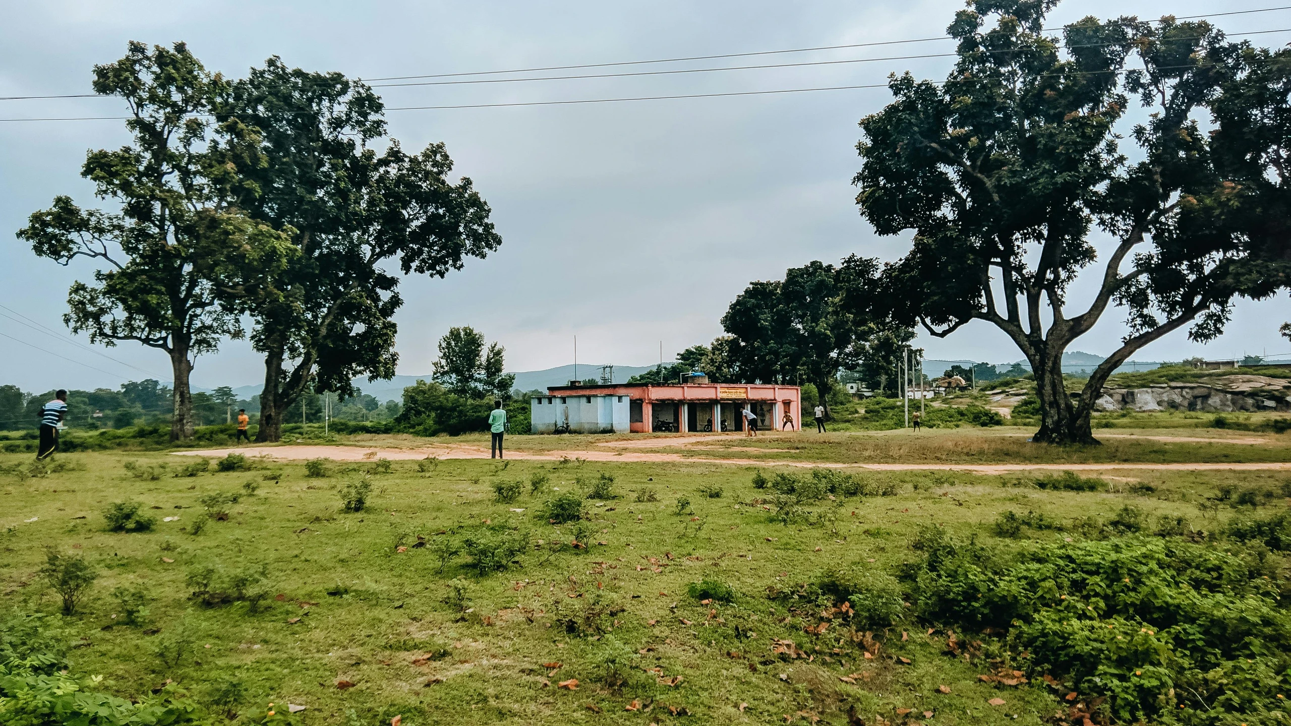 a small red shed surrounded by trees on a green field