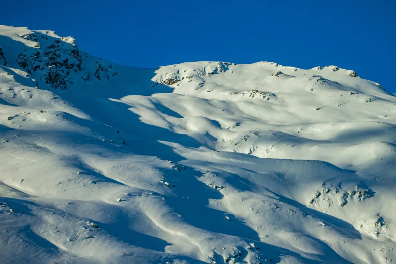 a big snow covered mountain that has a person on skis up side