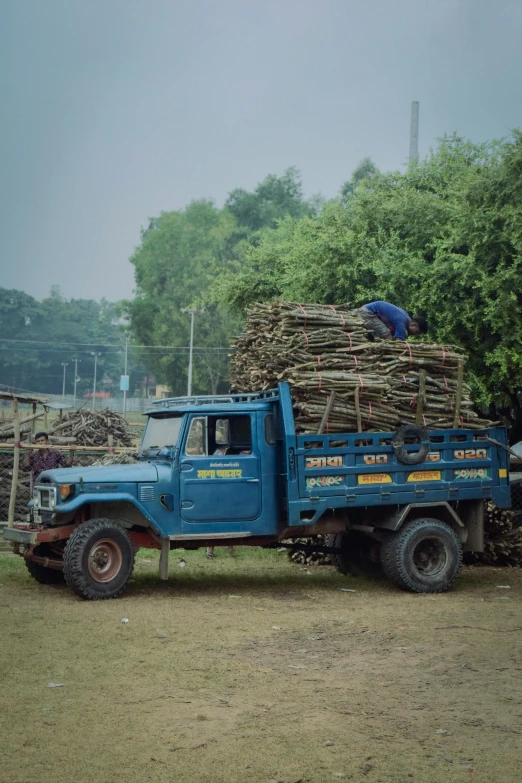 a blue pick up truck hauling a pile of wood