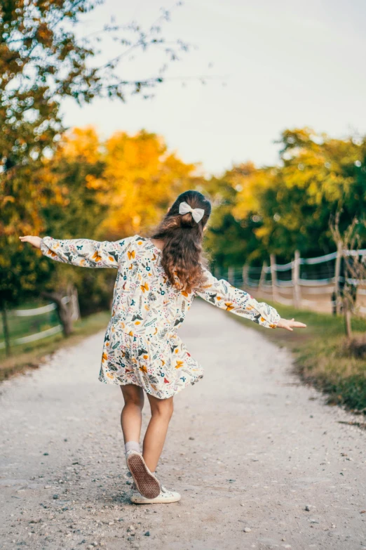 a  is running down a road with her arms spread wide