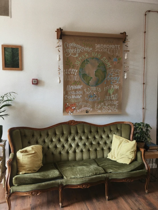 a green sofa with a poster on the wall behind it