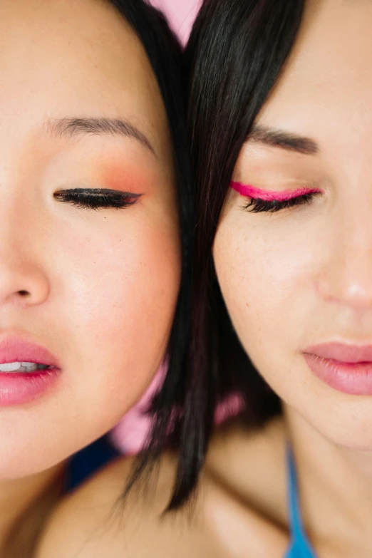 two asian woman posing for the camera with pink and yellow makeup