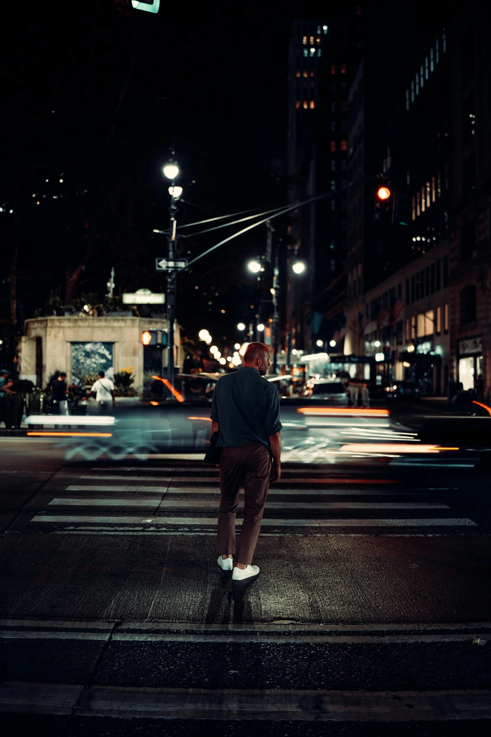 a young person is waiting at an intersection in the dark