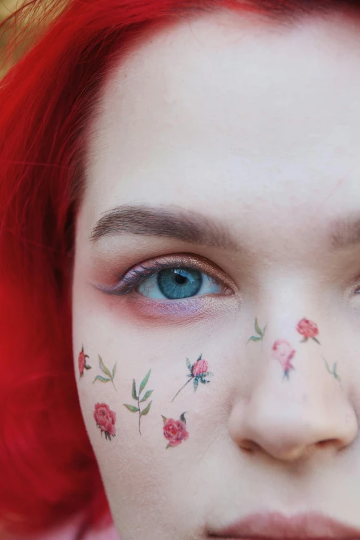 the girl has bright red hair and a rose painted on her cheek