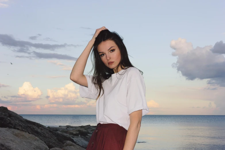 a girl with a white shirt and red skirt standing by the water