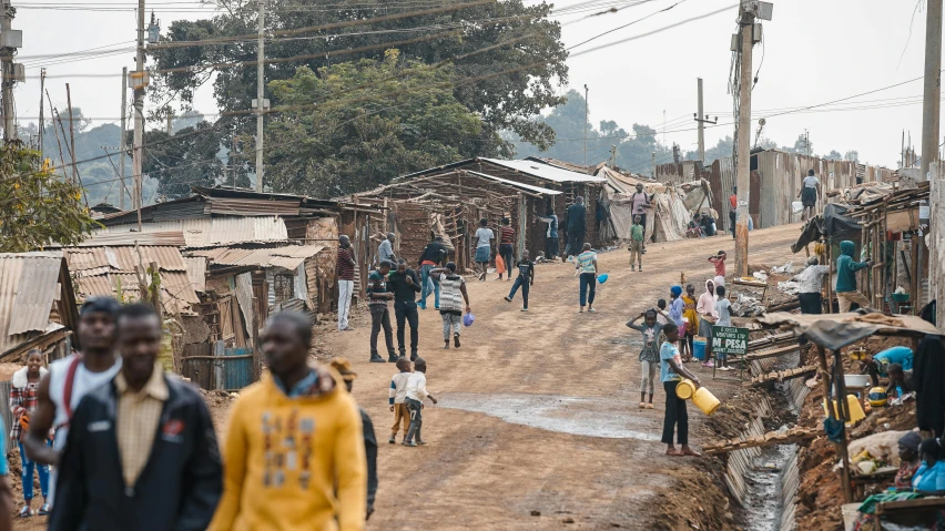 people are walking down a dirt road in a small area