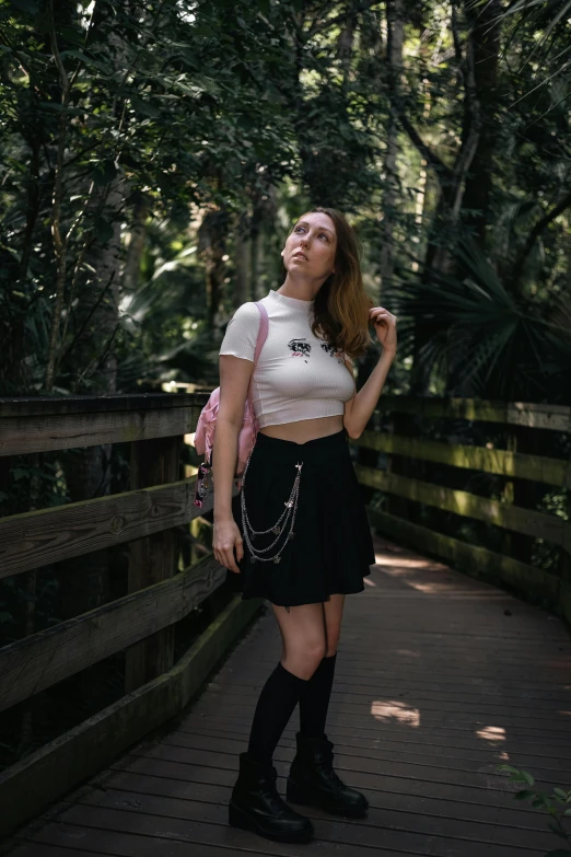 a woman with her head bowed wearing a skirt and a crop top