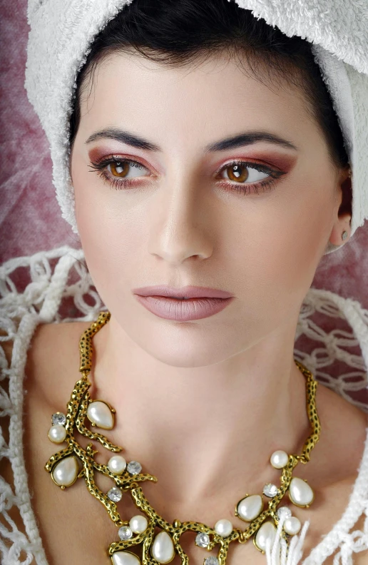 a woman wearing an ornate gold necklace with pearls