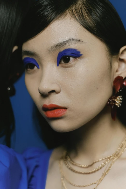 two women are wearing blue makeup and orange accessories