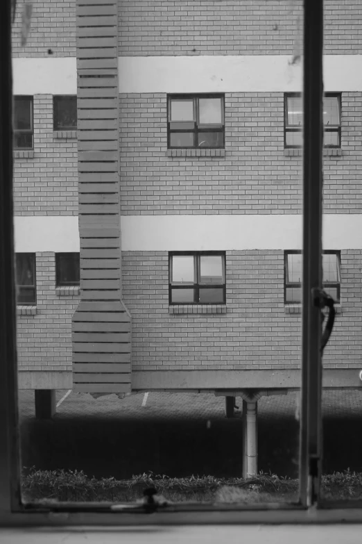 a city view out a window, showing the side of a building with a parking meter