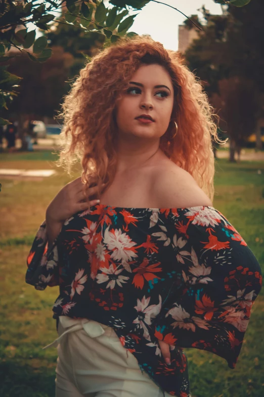 a woman standing in the grass near a tree