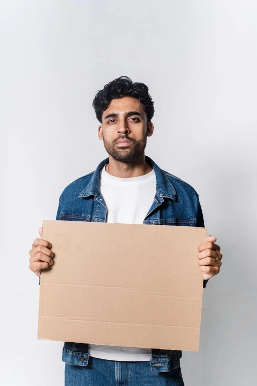 a man with a beard holds a cardboard sign