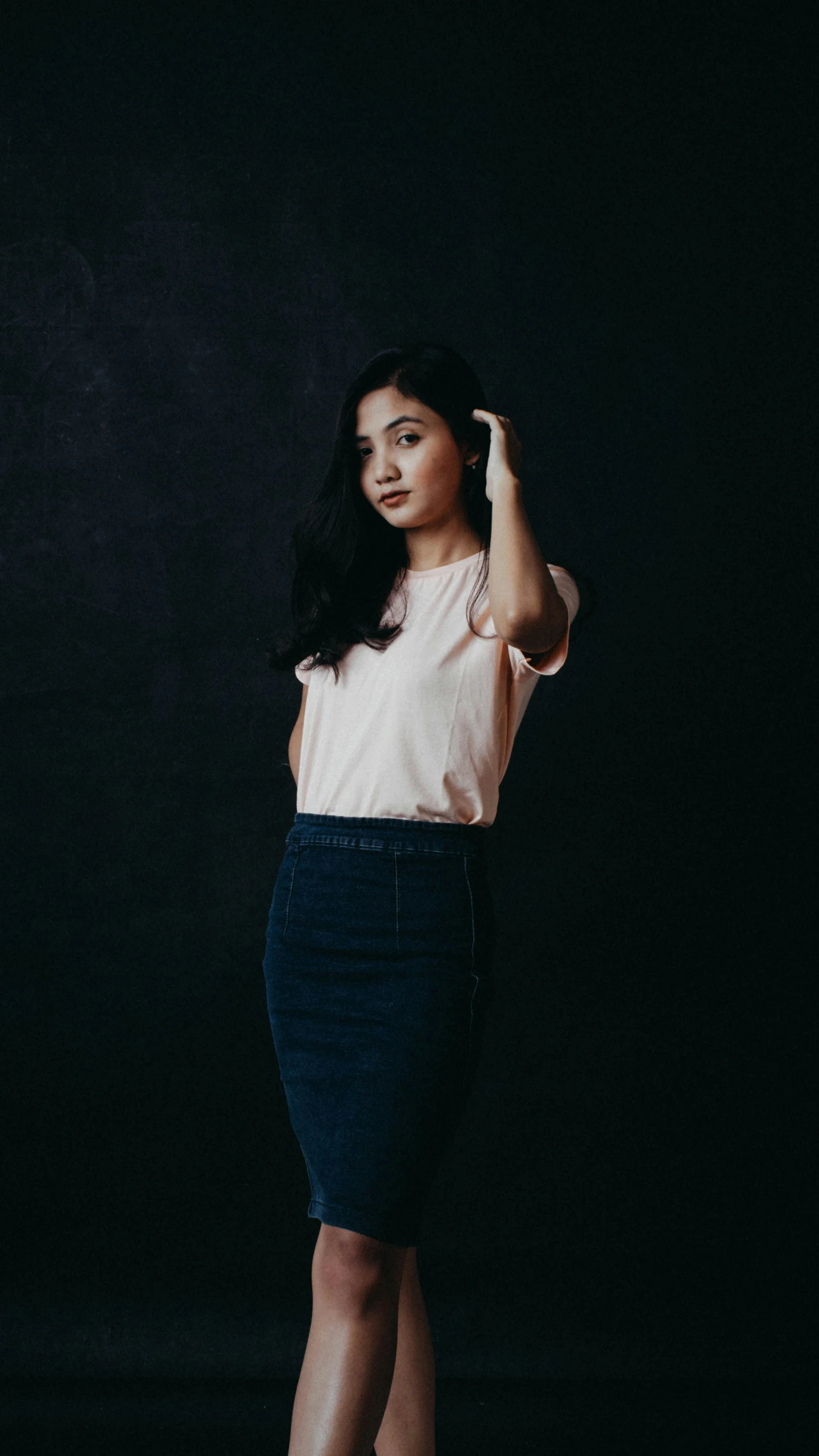 a woman is leaning against a dark wall