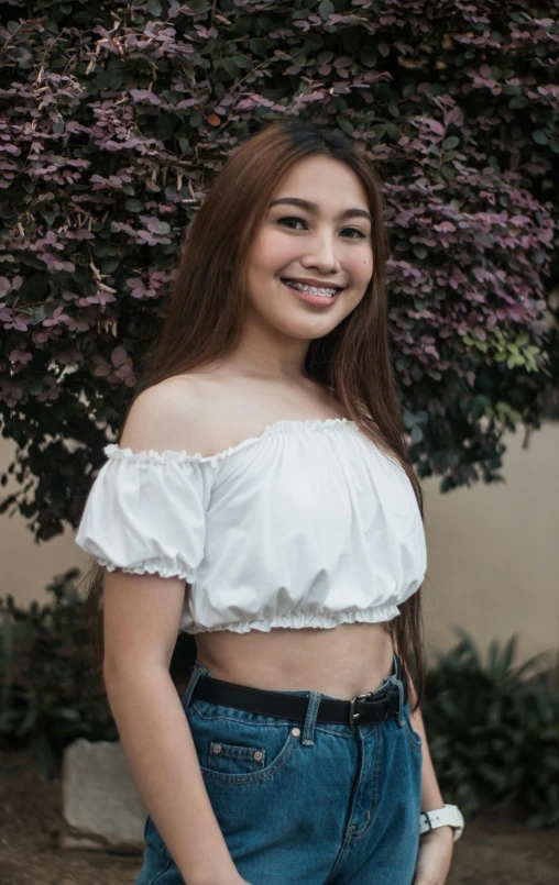 a beautiful young lady standing near some flowers