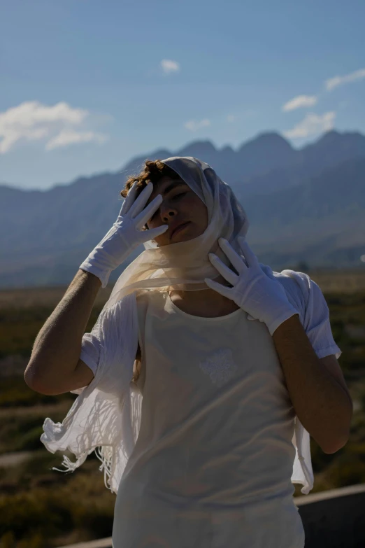 a woman standing in the sun wearing a white dress