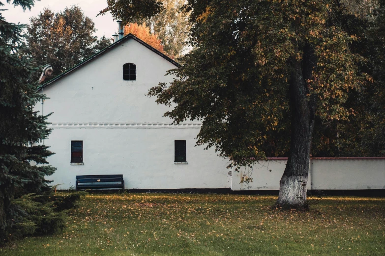 a white house in a park setting behind a tree