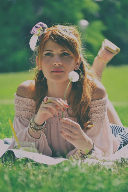 a girl sitting in the grass with her hands in her pockets