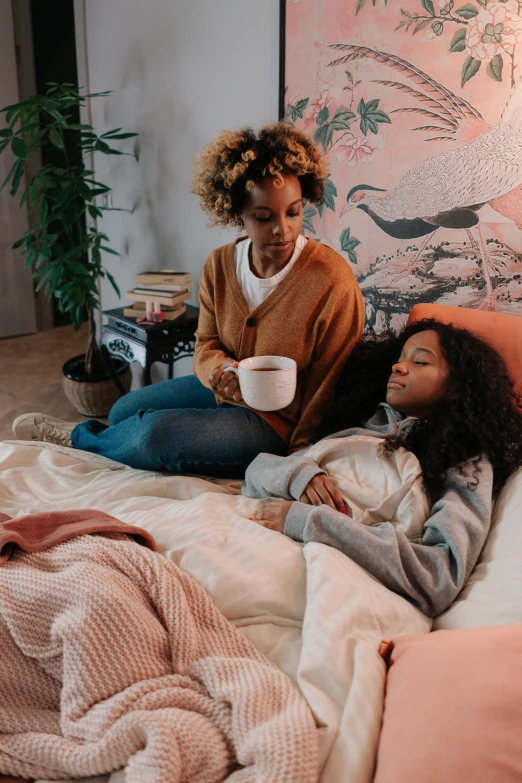 two women in pink and white sitting on a bed