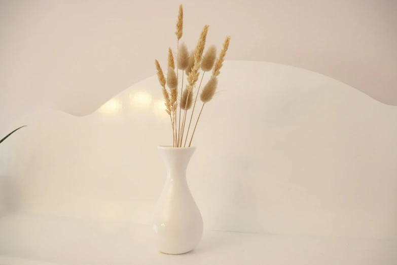 a white vase with reeds in it