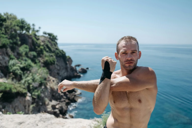 shirtless man holding a tennis racquet over his left arm