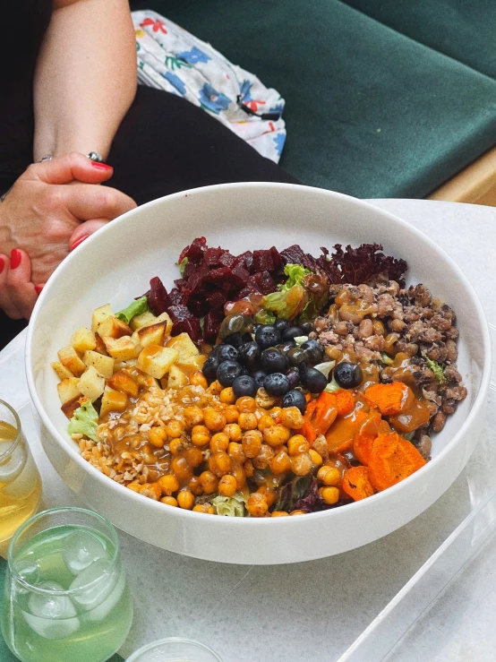 a bowl of food sits on a table with two glasses