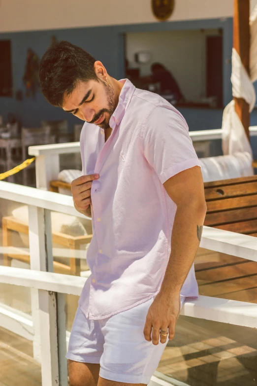 a man standing in shorts and a pink shirt