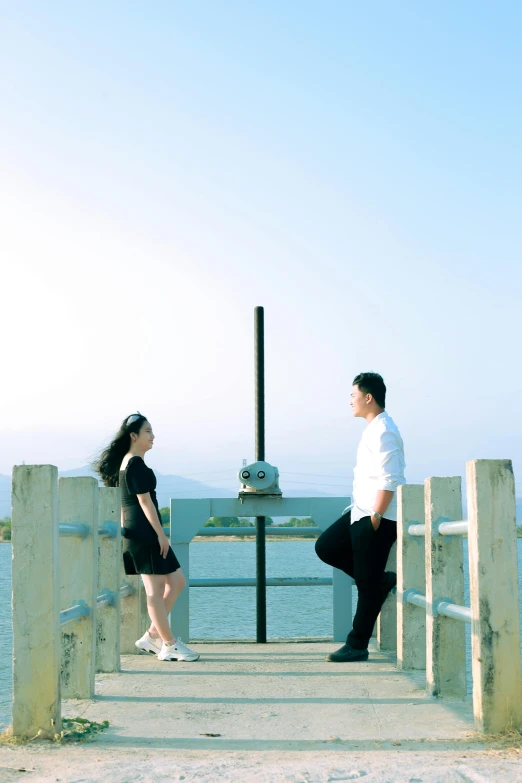 the couple is standing on a dock next to water