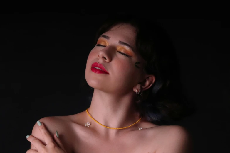 a model with bright eye makeup and a golden necklace