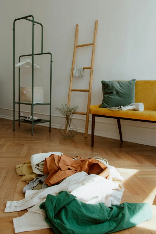 clothing laying out on the floor with ladder in the background