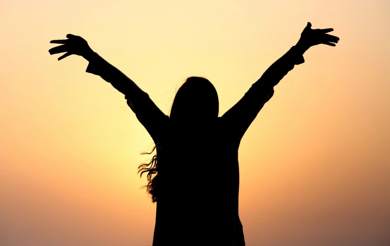 woman arms up in front of the sun