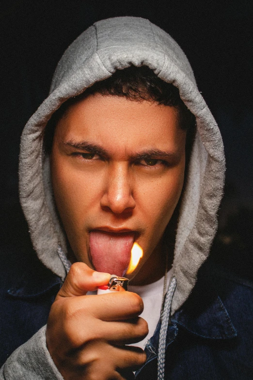 a person wearing hoodie and holding a lit cigarette