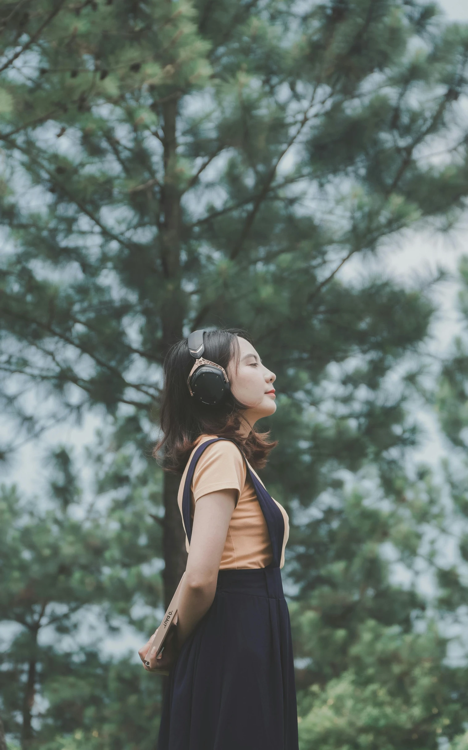 a woman standing in front of trees looking up