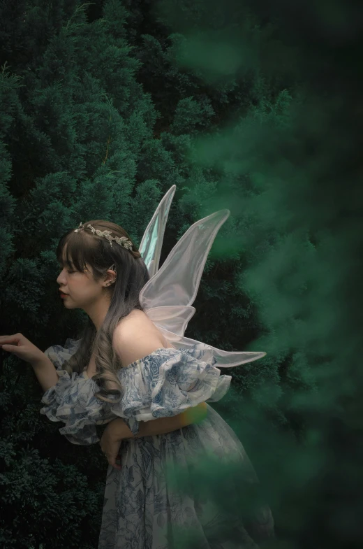 an angel girl with blue dress and wings in the woods