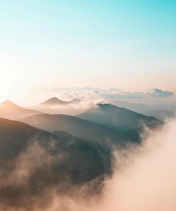 a view of the tops of mountains in the mist