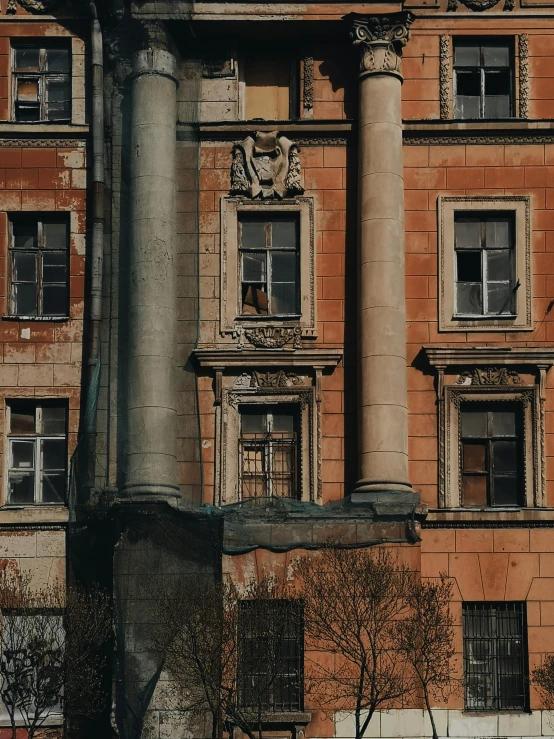 old looking brown building with many windows and columns