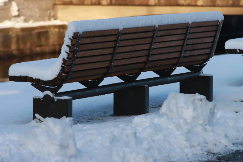 a wooden bench covered in snow on top of snow