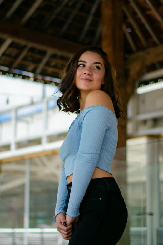 a young woman is standing and smiling with her hands behind her back