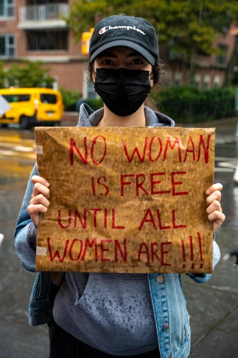 a woman with a face mask holds up a sign