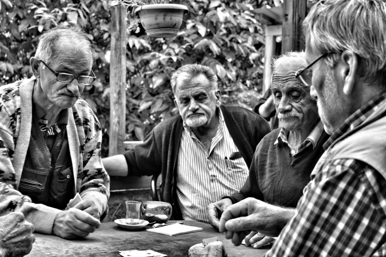 black and white image of men sitting at table playing card game