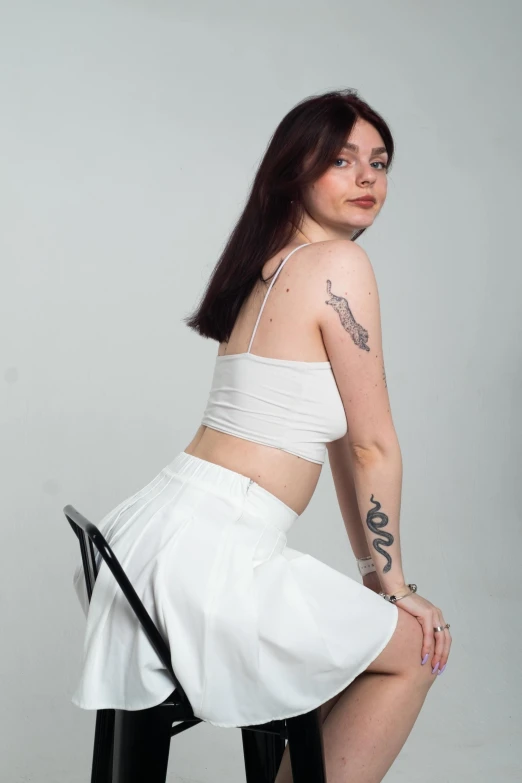 a woman in a white top sitting on top of a stool