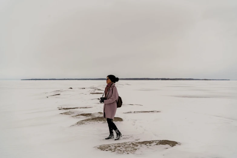 a woman in a pink coat walks through snow