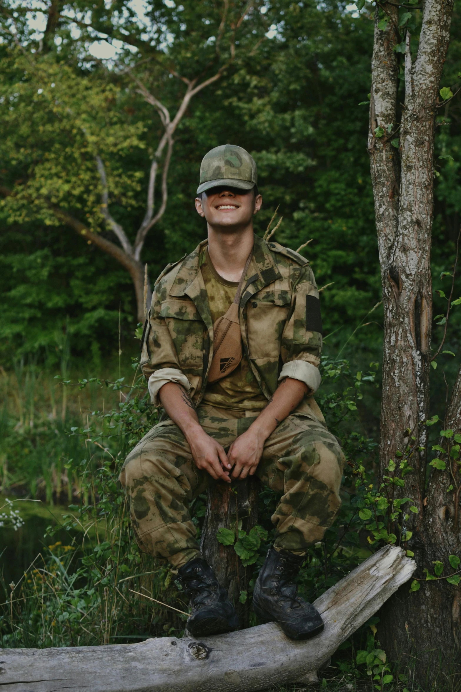 man in military outfit sitting on a log posing
