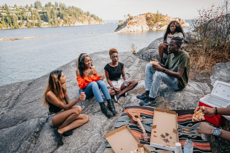 several people sitting on rocks by the water having some fun